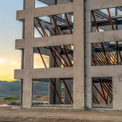 Square frame Exterior of modern building under construction against sky and clouds at sunset