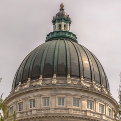 Fototapeta na wymiar Square Famous Utah State Capitol Building dome framed with trees against cloudy sky