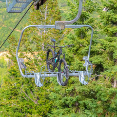 Fototapeta na wymiar Square frame Mountain bike on a lift against trees in Park City ski resort during off season