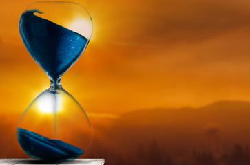 Falling sand in a hourglass with twilight sky background