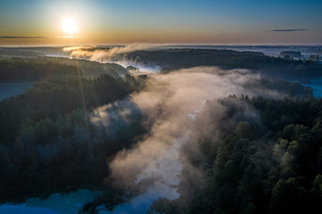 Flying above stunning mist over river in sunrise in autumn