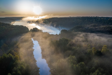 Fototapeta premium Aerial view of fog over river with rays in autumn