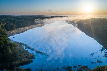 Flying above wonderful fog over river with rays in autumn