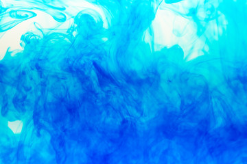 Abstract background. Blue ink in water, photographed in motion. Color drop swirling. Colorful cloud of paint on white.