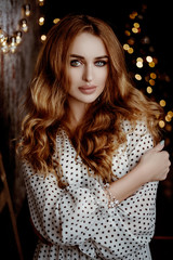 Lovely girl in a white  dress in the New Year’s interior. Woman at home at Christmas time in a...