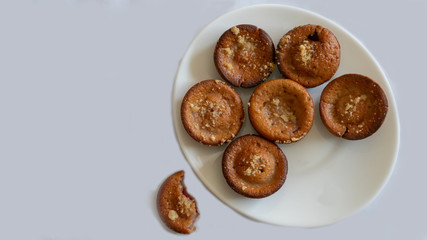 Bite soft yummy muffin out of the served plate on isolated tabletop. Homemade sweet baked muffins. Temptation Dessert pastry cooked