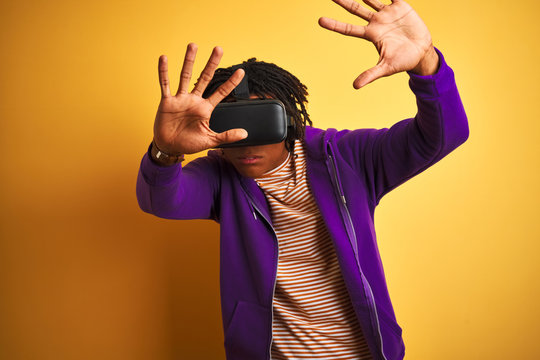Young african american man playing virtual reality game using goggles