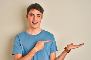 Teenager boy wearing casual t-shirt standing over isolated background amazed and smiling to the...