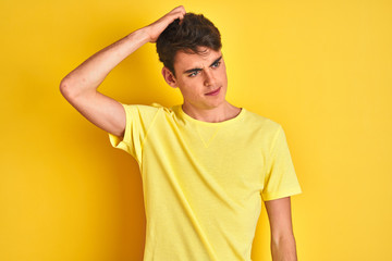Fototapeta na wymiar Teenager boy wearing yellow t-shirt over isolated background confuse and wonder about question. Uncertain with doubt, thinking with hand on head. Pensive concept.