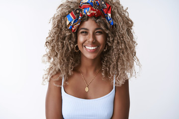 Cheerful charismatic african-american curly blond woman in stylish outfit, piercing smiling toothy,...