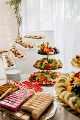 Sweet food on the table. Wedding feast. Catering food, service. Cafeteria, restaurant. Table with desserts and candles. Romantic design. Candy bar. Dessert table for a party.