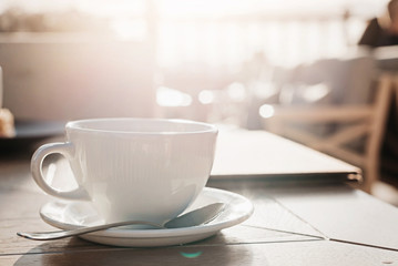 White big cup of delicious coffee on wooden table in sunset light with copy space.