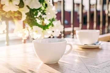 White big cup of delicious coffee on wooden table in sunset light with copy space.