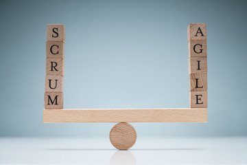 Stack Of Wooden Scrum And Agile Blocks On Seesaw