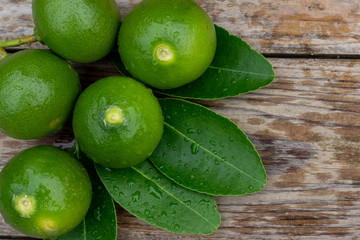 Fresh limes or green lemons on wood table background. Top view with copy space