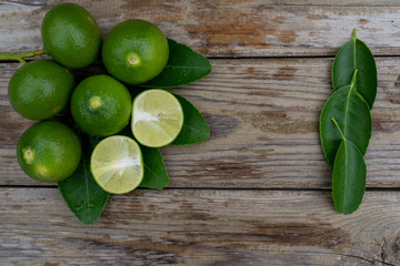 Fresh limes or green lemons on wood table background. Top view with copy space