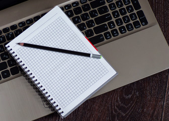 Work laptop with Notepad on wooden Desk. Keyboard from laptop and spiral notebook designer.