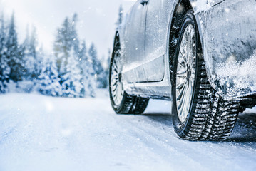 Winter tire. Car tire on snow road. Tires on snowy road detail. - obrazy, fototapety, plakaty