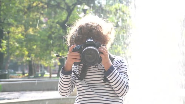 Bambino impara a fotografare con una macchina fotografica reflex professionale in un parco 