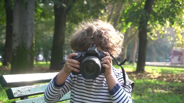 Bambino impara a fotografare con una macchina fotografica reflex professionale in un parco 