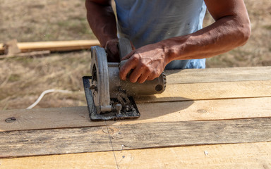 A worker cuts a wooden beam at a construction site