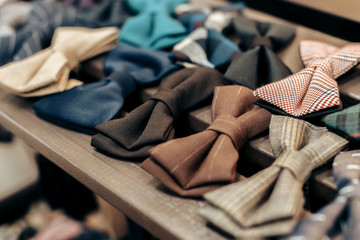 colored bow ties lie on a wooden brown shelf