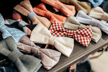colored bow ties lie on a wooden brown shelf