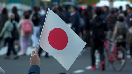 TOKYO, JAPAN - 10 NOVEMBER 2019 : People waving the national flag of Japan at the street. Blurred crowd of people in the background. Scenery at the Royal parade. Slow motion shot. - Powered by Adobe