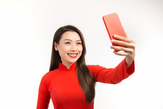 Beautiful Asian woman taking selfie with her phone over white background.
