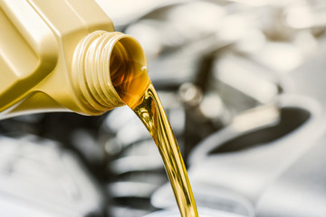 Pour yellow motor oil into car engine. Maintenance service change liquids and fluid.