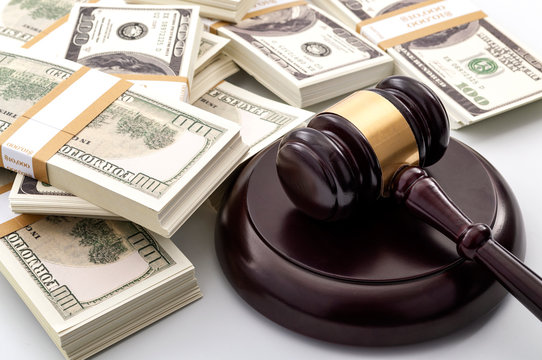 Money influence in the legal court system, corruption, auction bidding and bankruptcy conceptual idea with wood judge gavel and wad or bundle of cash on white background