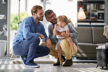 gay parents with child in store for household - obrazy, fototapety, plakaty