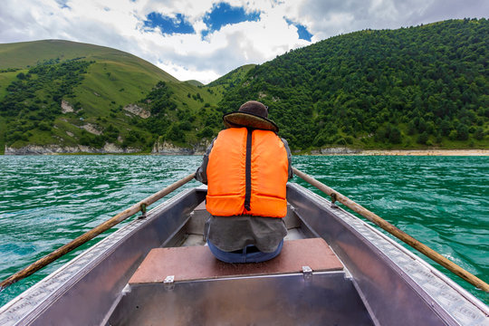 man rowing on a boat back view Beautiful mountain lake Kezenoy Am or Kezenoyam in Chechen republik in Russia