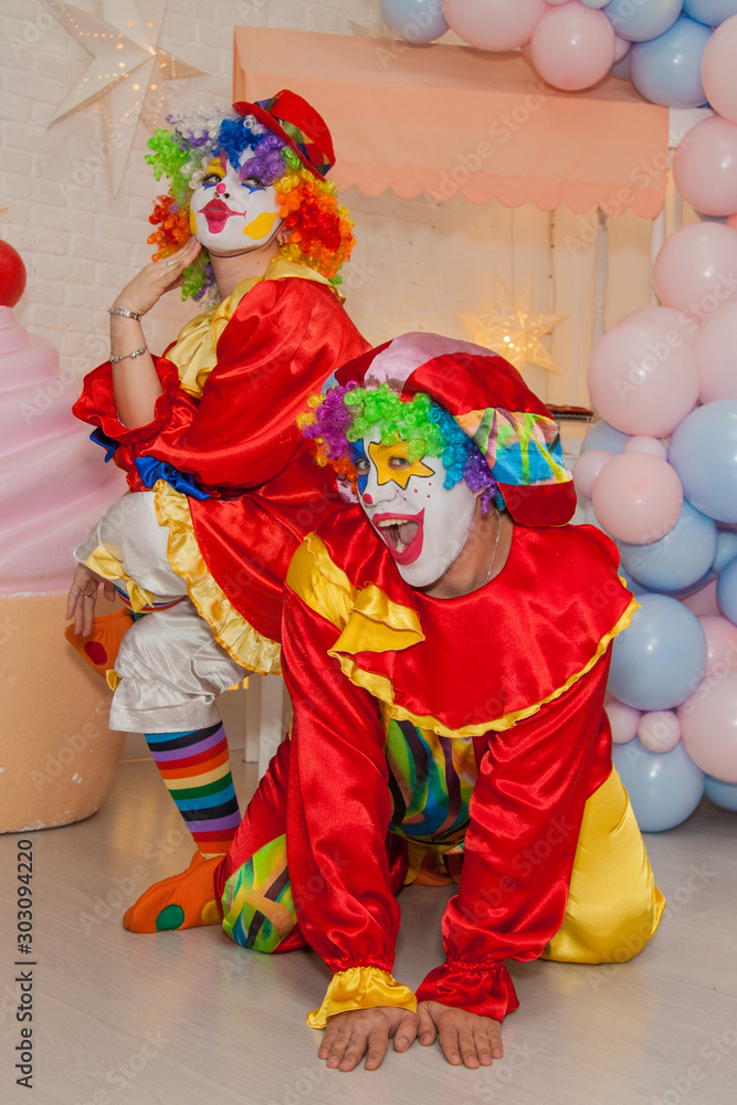 Wall mural Funny clowns from the circus. Clown boy and clown girl show emotions