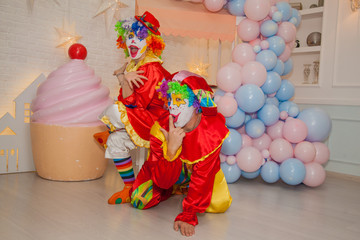 Fototapeta na wymiar Funny clowns from the circus. Clown boy and clown girl show emotions