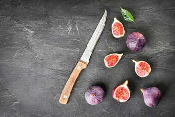 Figs fruits on dark stone table with knife, top view. Ripe fig citrus on black board or background copy space.