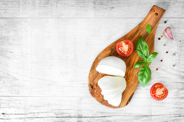 Fresh finest tomatoes on white rustic board with basil and mozzarella cheese top view. - obrazy, fototapety, plakaty