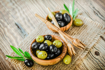 Fresh olives in olive bowl on old wooden table top view.