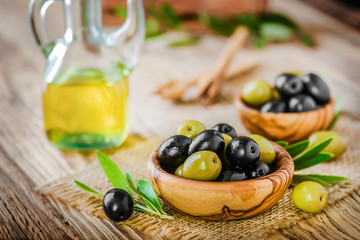 Fresh olives in olive bowl on old wooden table top view.