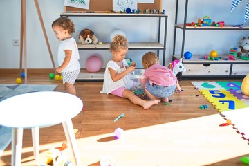 Adorable toddlers playing around lots of toys at kindergarten