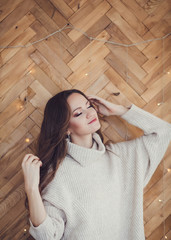 cute girl in sweater with closed eyes on wooden background