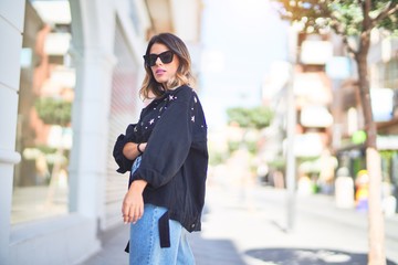 Fototapeta premium Young beautiful woman wearing sunglasses smiling happy and confident. Standing and walking at town street