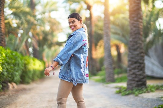 Young beautiful woman wearing denim jacket smiling happy and confident. Standing with smile on face at the town park