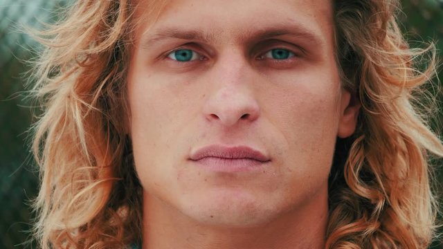 portrait of handsome blue-eyed guy with blond long curly hair