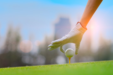 hand of young woman golf player holding golf ball laying on wooden tee, prepare and ready to hit...