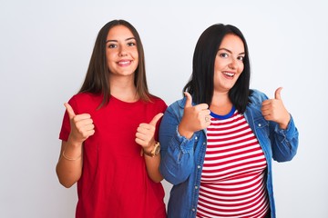 Young beautiful women wearing casual clothes standing over isolated white background success sign doing positive gesture with hand, thumbs up smiling and happy. Cheerful expression and winner gesture.