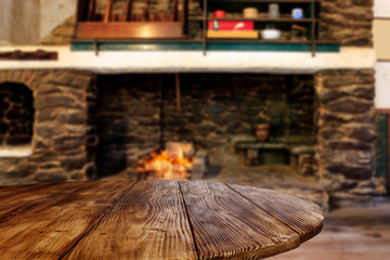 Wooden brown old table desk of free space for your decoration.Christmas fireplace and home interior.Cold december winter time and orange color of warm fire.Copy space and dark mood shadows.