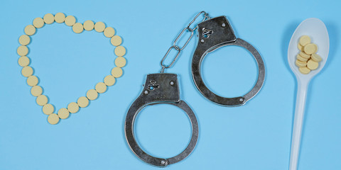 Pills on a blue background whith spoon and handcuffs.