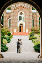 A loving couple stands in a churchyard