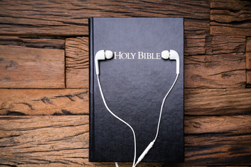 Headphones And Bible Over Wooden Surface